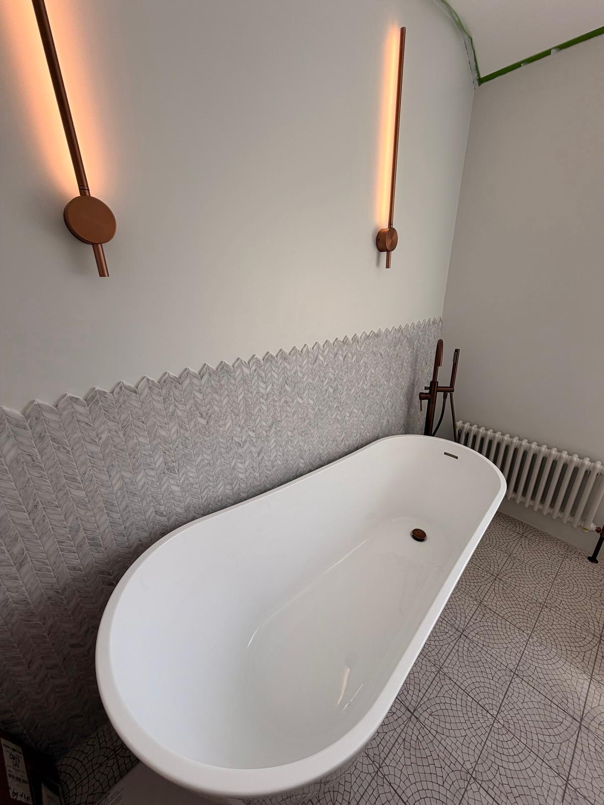 Freestanding bath with copper fittings and marble herringbone tiling