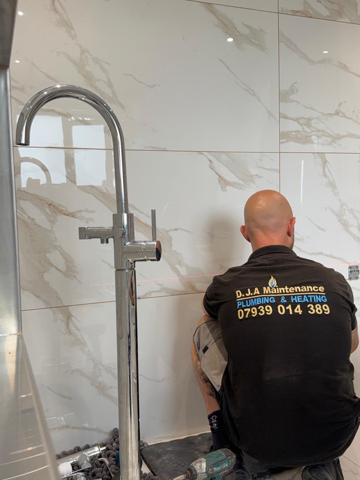 Fitting a chrome floor-standing bath tap against marble tiling