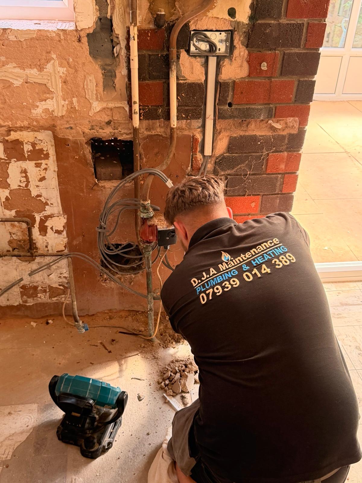 DJA Maintenance engineer re-piping behind an exposed brick wall